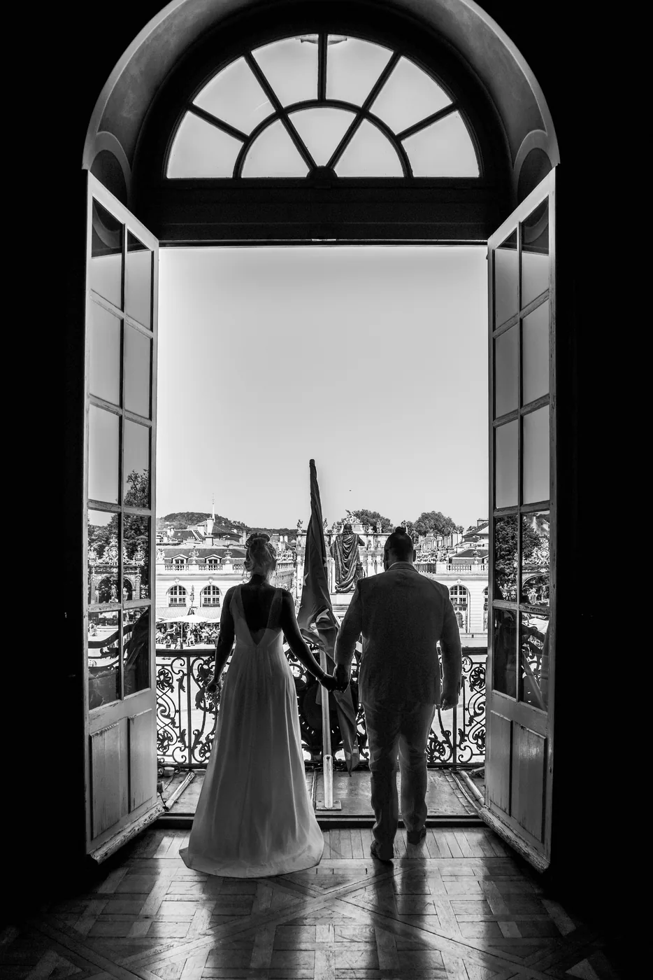 Mariés de dos sur le balcon de l'hôtel de ville de Nancy, face à la place Stanislas, photo de mariage en noir et blanc