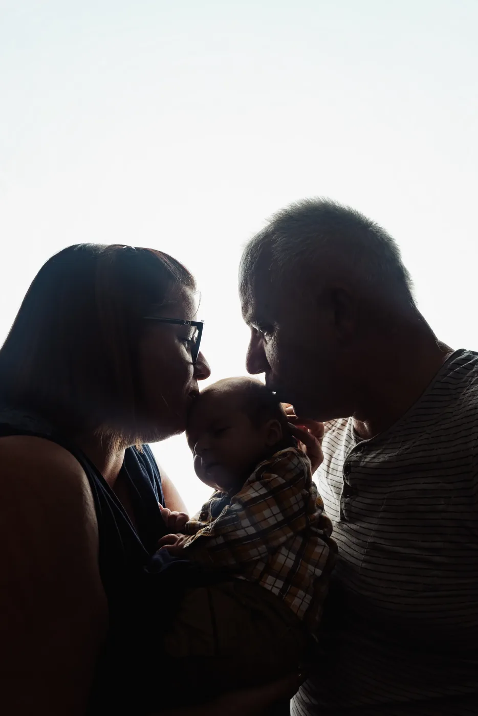 Parents embrassant leur nouveau-né en contre-jour - photographe naissance Nancy